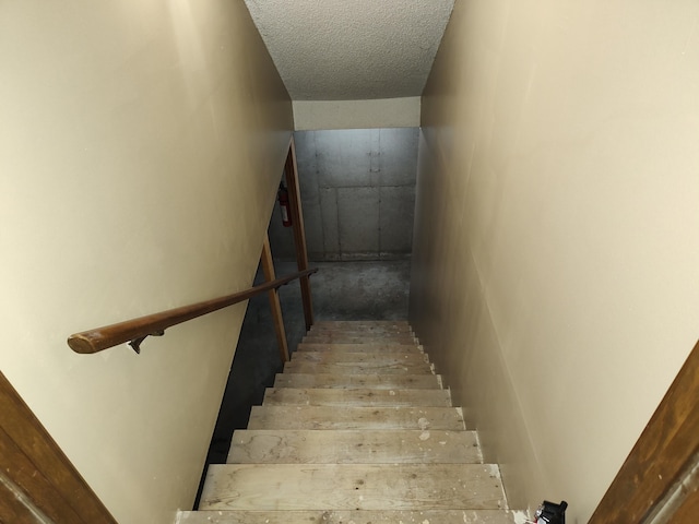 staircase featuring a textured ceiling