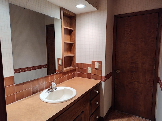 bathroom with tile walls, vanity, and wallpapered walls