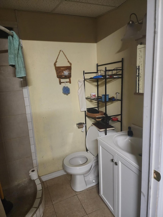 bathroom with vanity, a stall shower, a drop ceiling, tile patterned flooring, and toilet