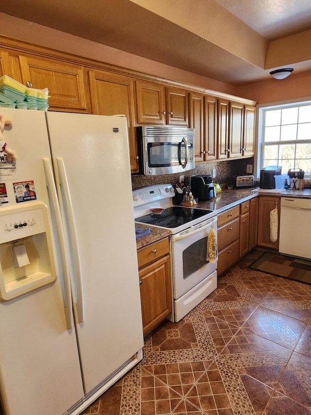 kitchen with white appliances, dark countertops, brown cabinets, and backsplash