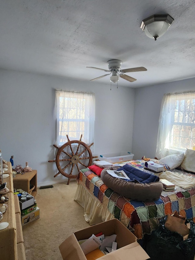 carpeted bedroom with multiple windows and a ceiling fan