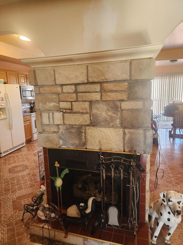 room details with white appliances, arched walkways, and a stone fireplace