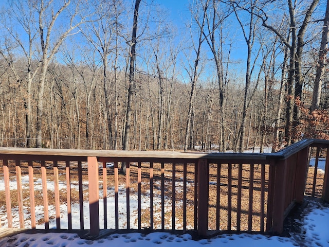 snow covered deck featuring a forest view