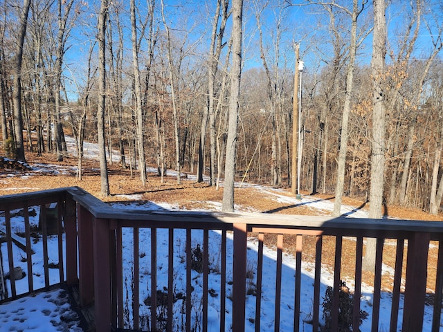 snow covered deck with a view of trees