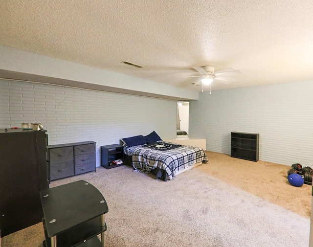 carpeted bedroom featuring visible vents, brick wall, a textured ceiling, and a ceiling fan