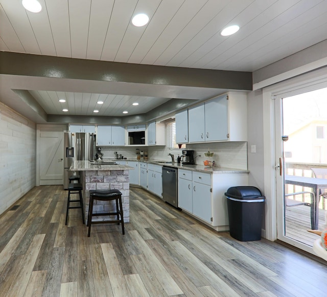 kitchen with a breakfast bar, tasteful backsplash, wood finished floors, stainless steel appliances, and wood ceiling