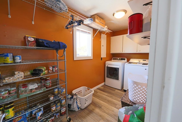 clothes washing area featuring cabinet space, washing machine and dryer, light wood-style floors, and baseboards