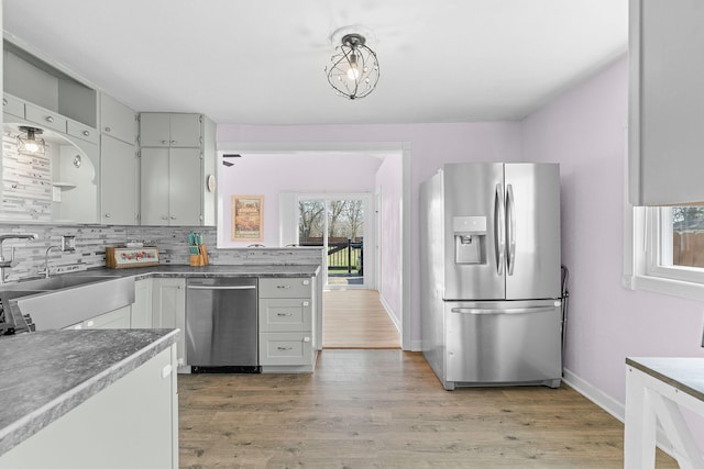 kitchen featuring baseboards, open shelves, decorative backsplash, appliances with stainless steel finishes, and light wood-type flooring