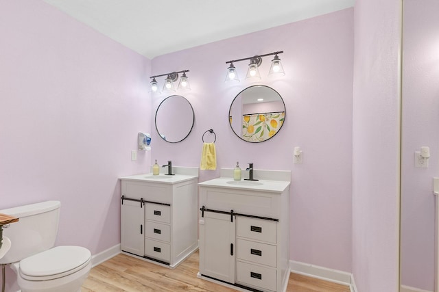 full bath featuring a sink, baseboards, toilet, and wood finished floors