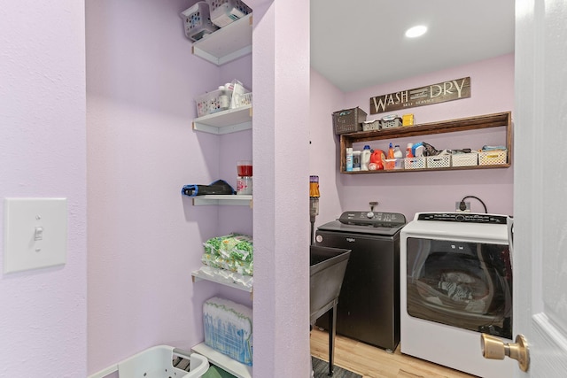 washroom with washing machine and dryer and wood finished floors