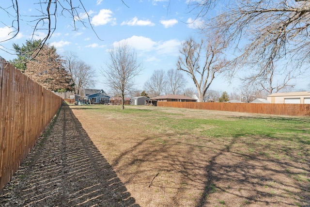 view of yard with an outbuilding, a fenced backyard, and a shed