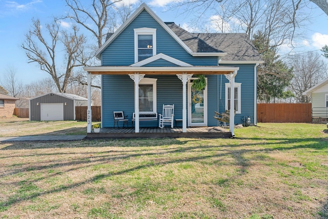 view of front of home featuring a front lawn, fence, a porch, a garage, and an outbuilding