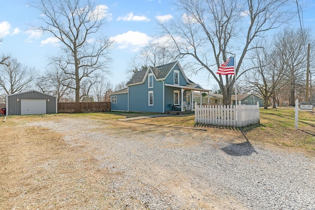 view of home's exterior with fence, driveway, covered porch, an outdoor structure, and a garage