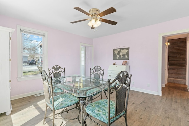 dining space with light wood-type flooring, baseboards, visible vents, and a ceiling fan