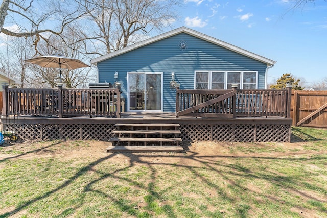 rear view of property featuring a deck, a yard, and fence