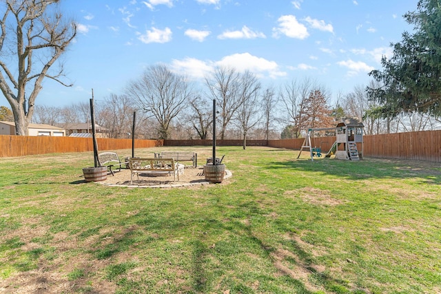 view of yard with a fire pit, a playground, and a fenced backyard