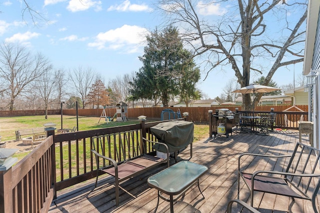 deck featuring a playground, a yard, and a fenced backyard