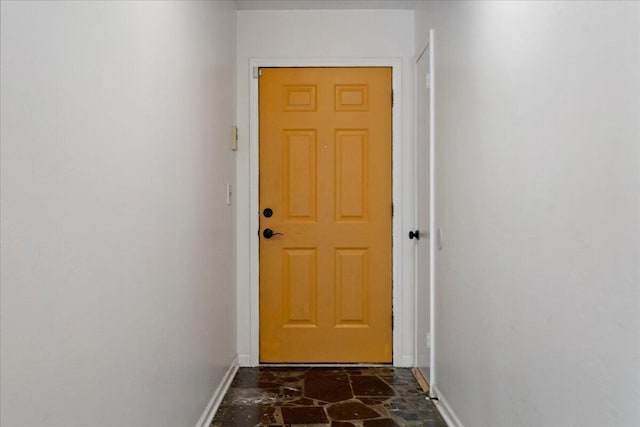 entryway featuring stone finish floor and baseboards