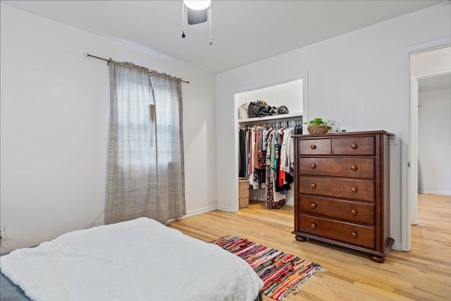 bedroom with a closet, ceiling fan, a spacious closet, and light wood finished floors