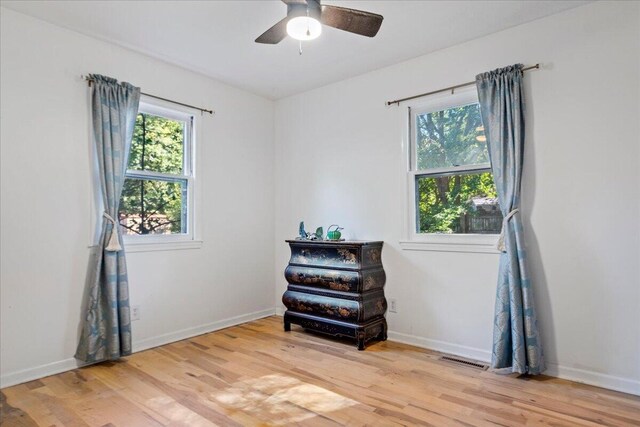 unfurnished room featuring light wood-type flooring, baseboards, visible vents, and ceiling fan