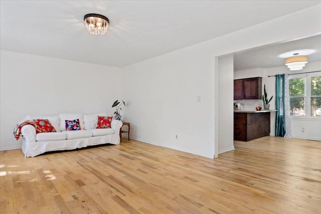 living area featuring a chandelier, baseboards, and light wood-style flooring