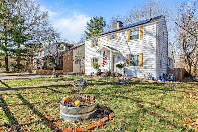 view of front of property with a front yard, solar panels, and a chimney