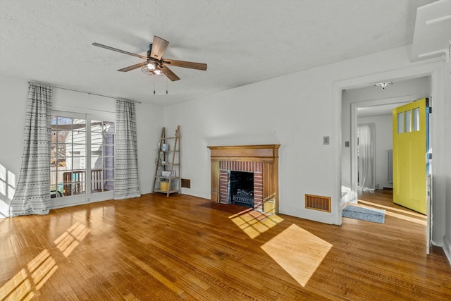 unfurnished living room featuring visible vents, a textured ceiling, a ceiling fan, and wood finished floors