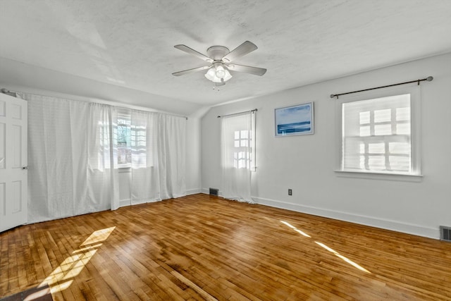 unfurnished room featuring hardwood / wood-style floors, a ceiling fan, visible vents, and a textured ceiling