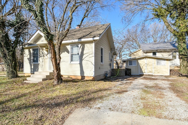 view of front of house with driveway, a storage shed, an outdoor structure, and a chimney