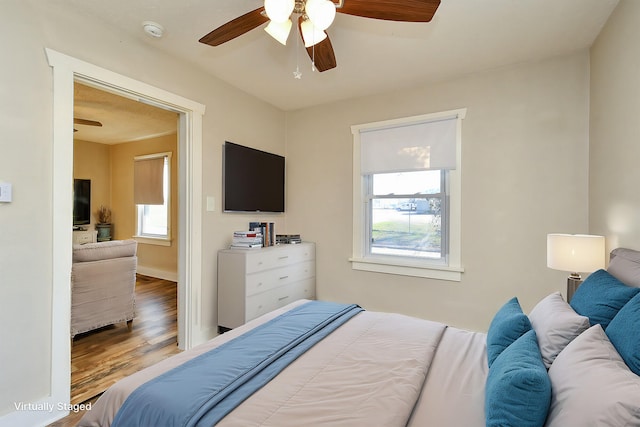 bedroom with a ceiling fan, wood finished floors, and baseboards