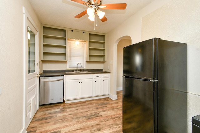 kitchen featuring open shelves, freestanding refrigerator, a sink, stainless steel dishwasher, and dark countertops