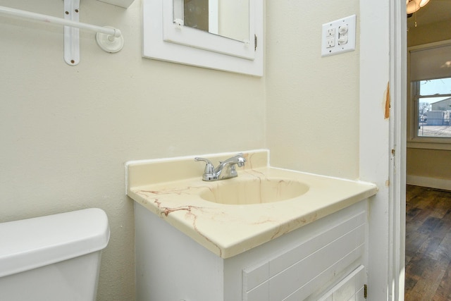 bathroom with toilet, vanity, and wood finished floors