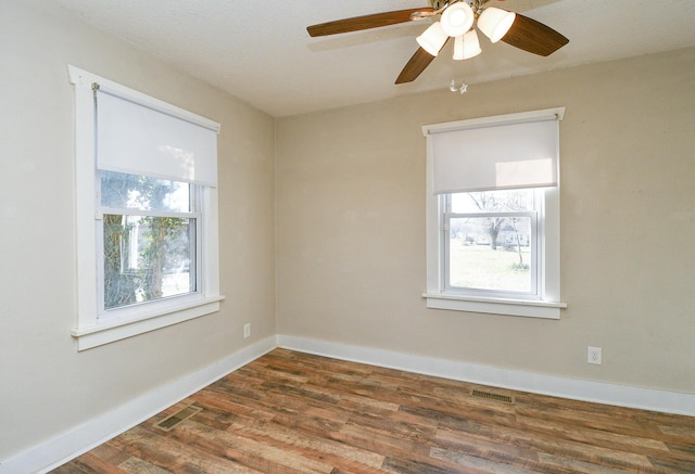 spare room featuring visible vents, baseboards, dark wood-type flooring, and a ceiling fan