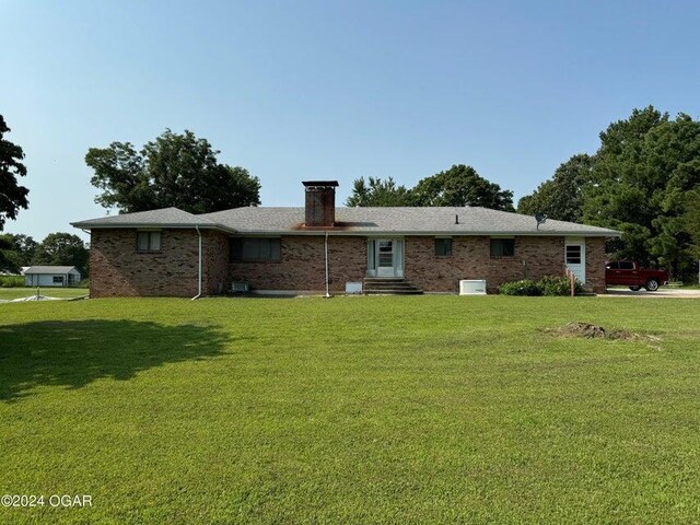 back of property featuring brick siding, a lawn, a chimney, and entry steps