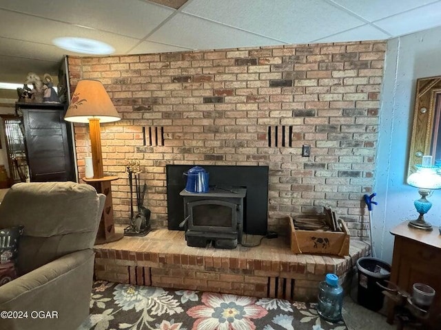 living area with a wood stove and a paneled ceiling