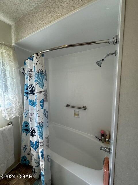 bathroom featuring shower / tub combo, wood finished floors, and a textured ceiling