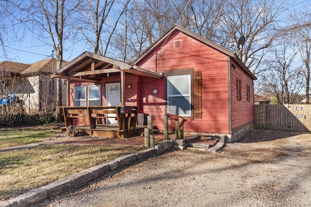 bungalow-style house with a porch, fence, and a front lawn