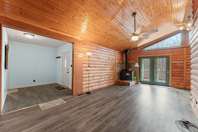 unfurnished room with a ceiling fan, wood finished floors, rustic walls, wood ceiling, and a wood stove