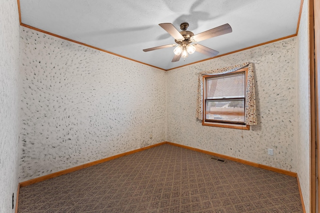 carpeted empty room featuring crown molding, a ceiling fan, visible vents, and baseboards