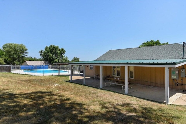 back of property with a patio, a fenced in pool, fence, and a lawn