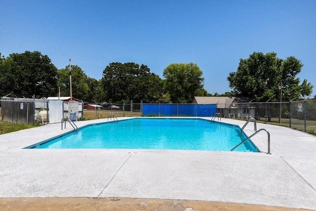 community pool with a patio area and fence