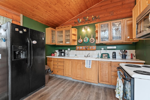 kitchen with stainless steel microwave, lofted ceiling, light wood-style flooring, black fridge with ice dispenser, and a sink