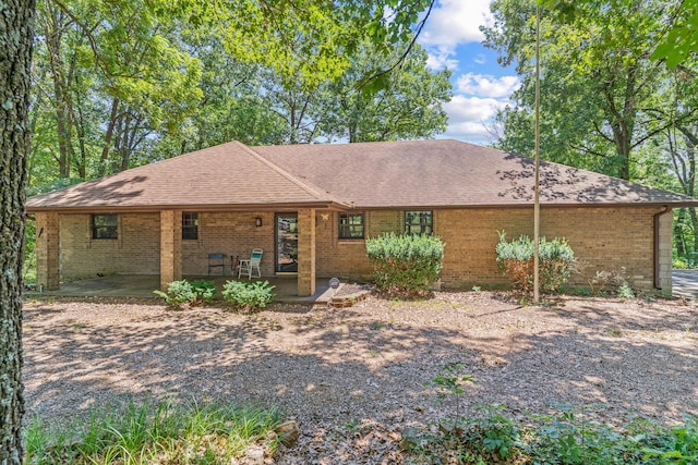 ranch-style house featuring brick siding and roof with shingles