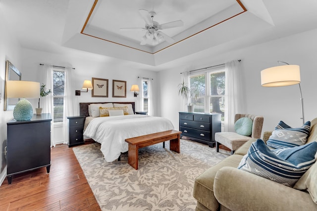 bedroom featuring a tray ceiling, wood finished floors, and ceiling fan