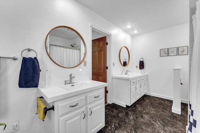 full bath featuring a sink, baseboards, marble finish floor, and two vanities