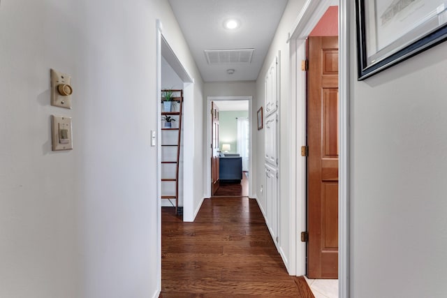 corridor featuring visible vents, baseboards, and wood finished floors