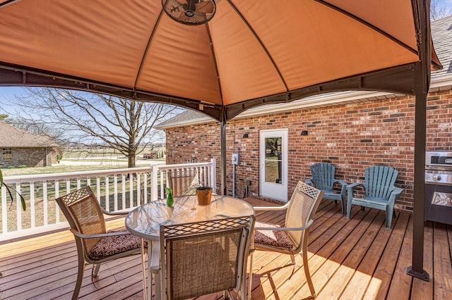 wooden terrace featuring a gazebo and outdoor dining space