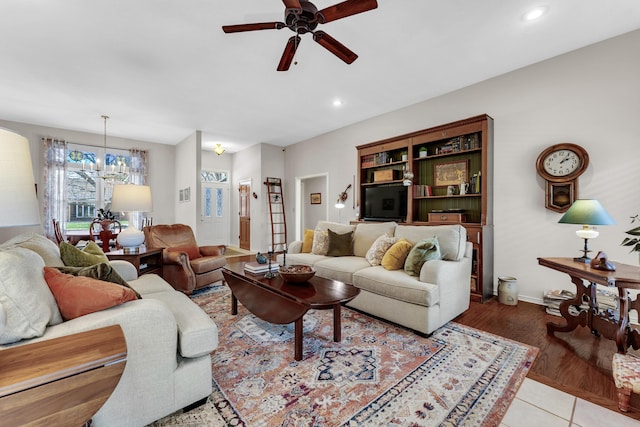 living area featuring wood finished floors, recessed lighting, ceiling fan with notable chandelier, and baseboards