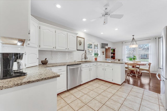 kitchen featuring white cabinetry, a peninsula, stainless steel appliances, and a sink