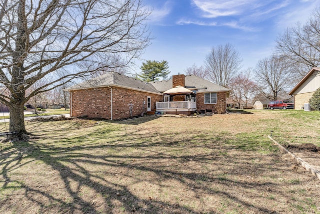 back of house featuring roof with shingles, a yard, a chimney, a deck, and brick siding